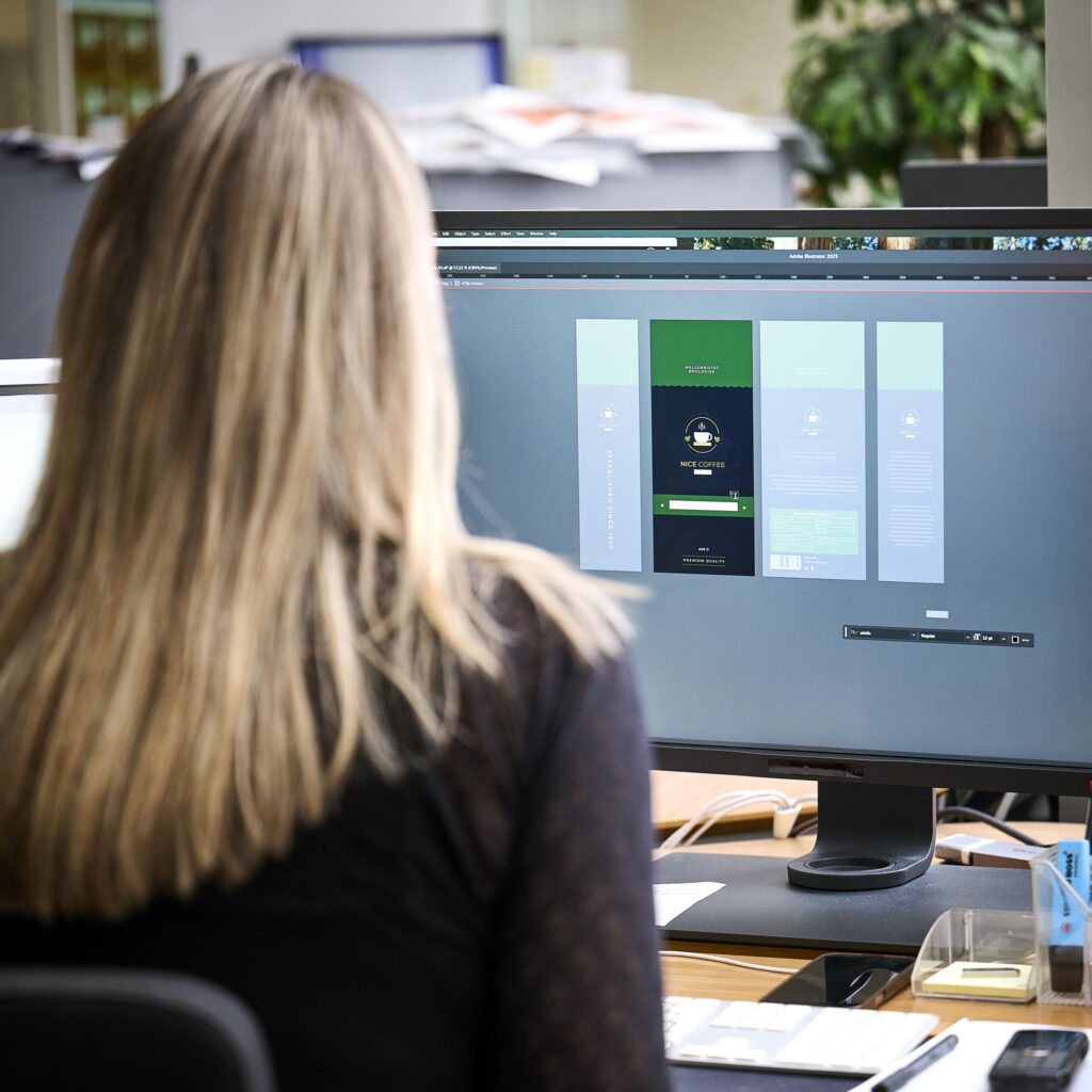 Kvinde arbejder på sin computer i hl-repros flexo afdeling med et emballage-design